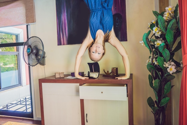 A woman is standing on his hands upside down in the living room.