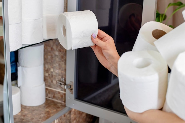 Photo a woman is stocking up toilet paper at home