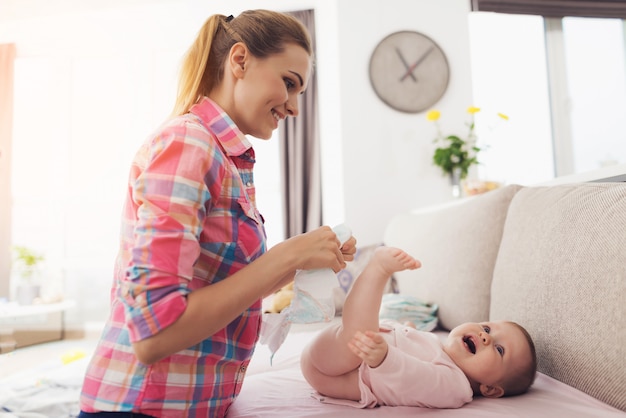 A woman is swaddling a small child on the couch.