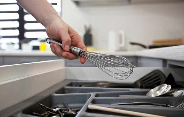 woman is taking kitchen equipment from shelf with kitchenware