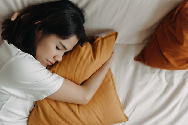 Женщина дремлет или спит на диване с желтой подушкой