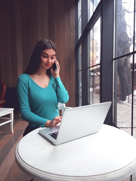 Woman is talking  and sitting near the window