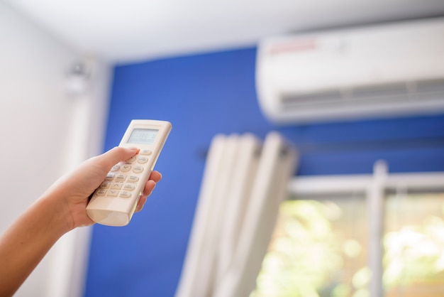 Woman is turning on air conditioner in home