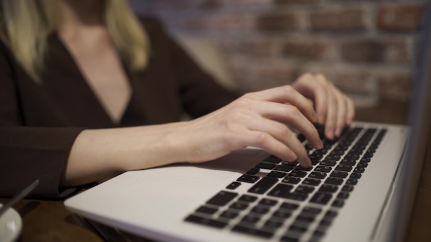 女性がノートパソコンのキーボードのクローズアップで入力しています。女性の手とラップトップ。 4KUHD。