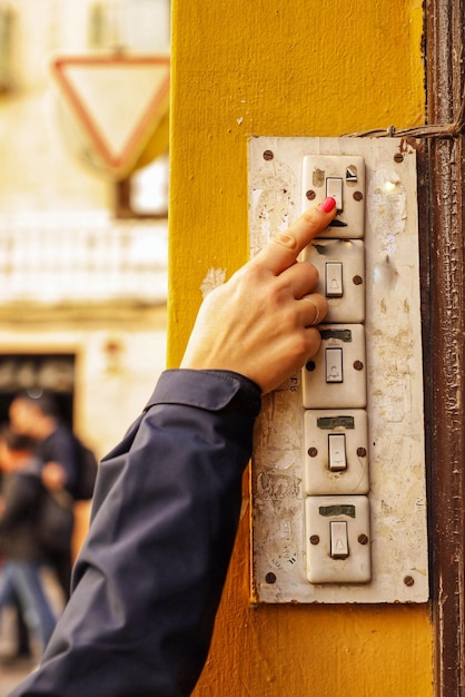 A woman is using a button on a yellow pole.