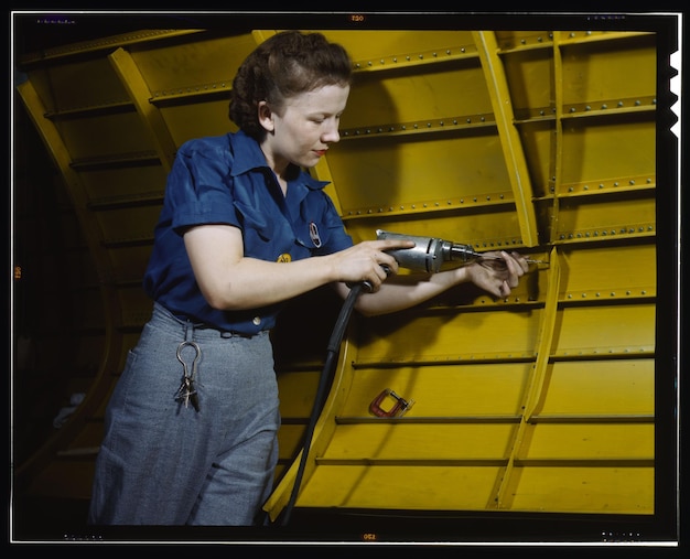 a woman is using a drill in a yellow container