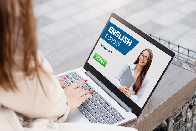 A woman is using a laptop with english school on the screen.