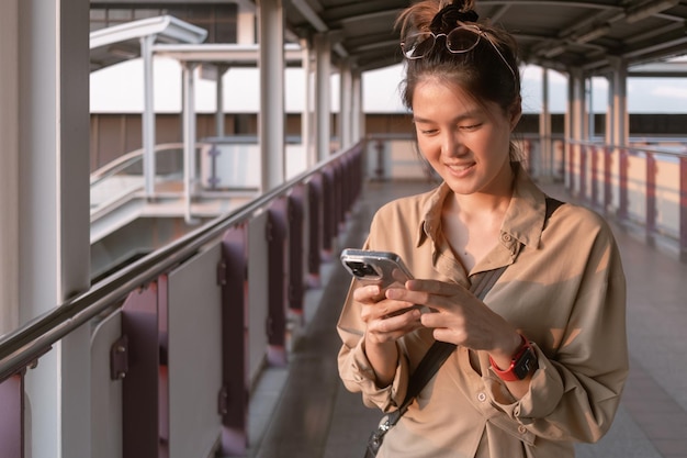 写真 女性がバンコクのシティブリッジで携帯電話を使っています