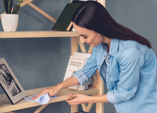 女性は自宅で家具を掃除しながらぼろを使用しています