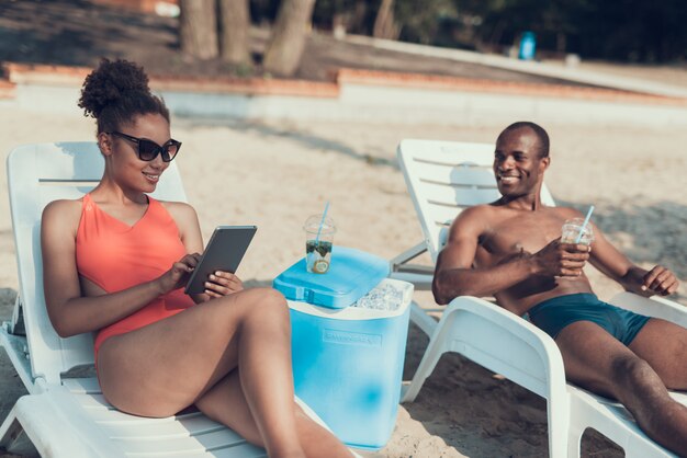 Woman is Using Tablet PC while Man Drinking Cocktail