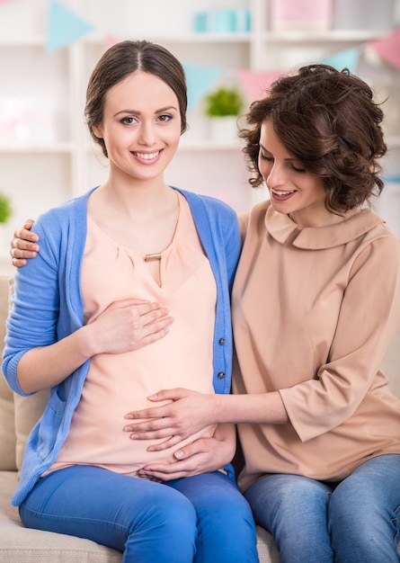 Woman is visiting pregnant friend at home.