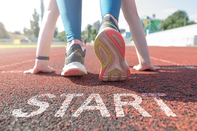 Una donna aspetta la partenza su una pista di atletica con la parola start incisa sul pavimento