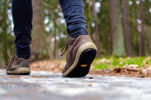 Una donna cammina su una strada scivolosa, la prima neve è caduta inaspettatamente nel parco, scarpe invernali, la strada è ricoperta di ghiaccio scivoloso. pericoloso. avvicinamento