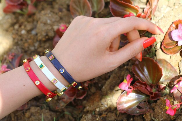 A woman is watering plants with a bracelet on her wrist.