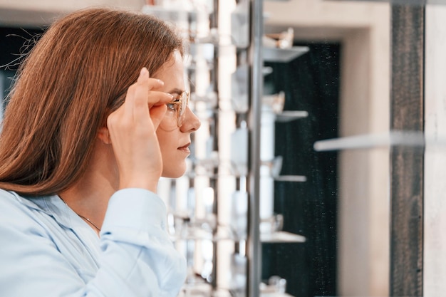 女性は店で眼鏡をかけている 視力を矯正するための正しい眼鏡を選ぶ