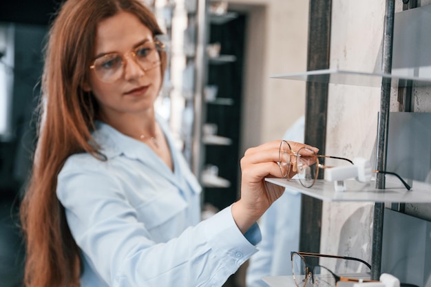 Woman is with glasses in the store Choosing right eyewear for correcting vision