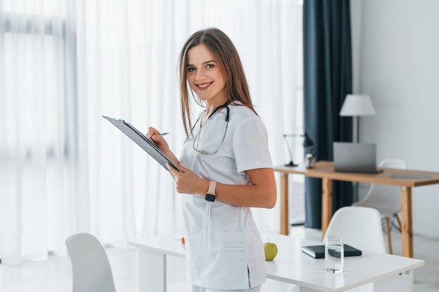 Woman is with notepad professional medical worker in white coat\
is in the office