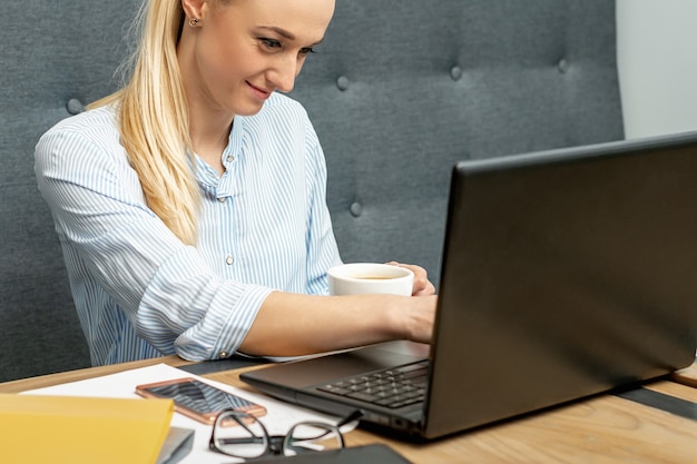 Woman is working on laptop at home office.