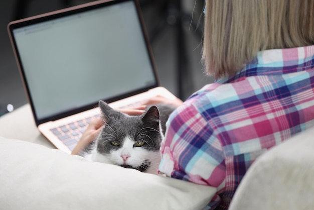 Photo woman is working on laptop with cat on couch