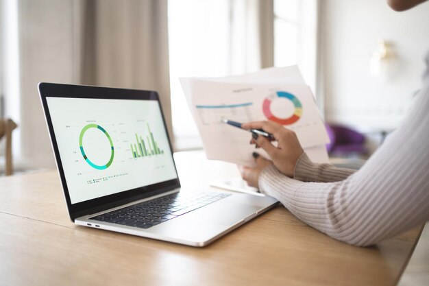 A woman is working in the office on a new project in a financial company using a laptop on the table