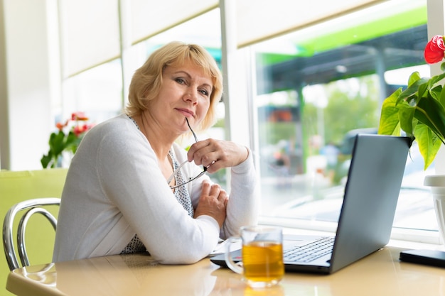 A woman is working with a laptop at a table in the room