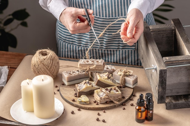 Photo woman is wrapping a beautiful natural soap decorated with coffee beans concept of interesting hobby and handmade gifts