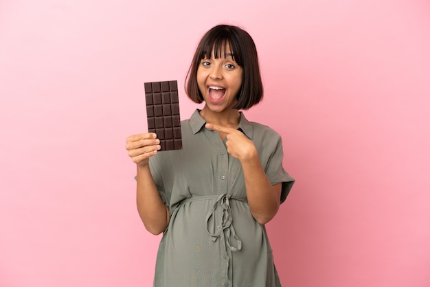 Woman over isolated background pregnant and holding chocolate