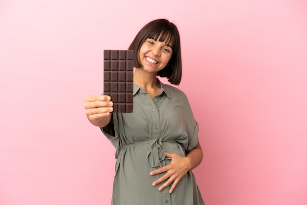 Женщина на изолированном фоне беременна и держит шоколад