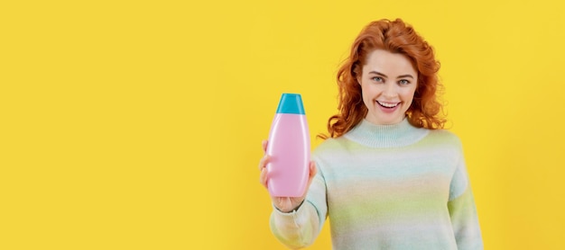 Woman isolated face portrait banner with copy space happy redhead woman with shampoo bottle shampooing hair in salon girl with hair conditioner