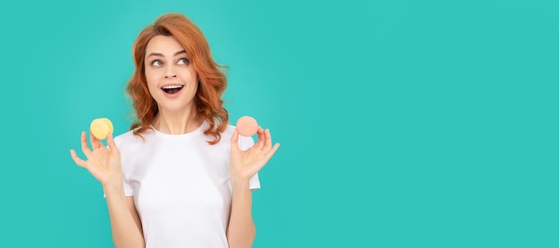 Woman isolated face portrait banner with mock up copyspace happy shocked woman hold sweet macaron french cookie on blue background