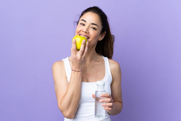 水のボトルとリンゴを食べて孤立した紫以上の女性