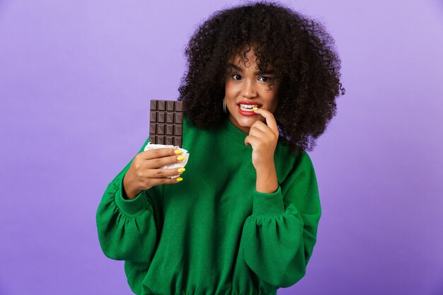 Woman isolated over violet space holding chocolate.