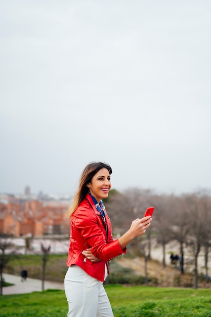 woman in jacket using phone in park