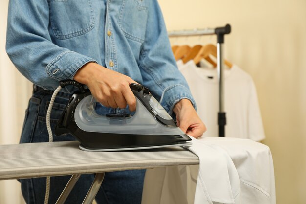 Photo woman in jeans ironing shirt with iron