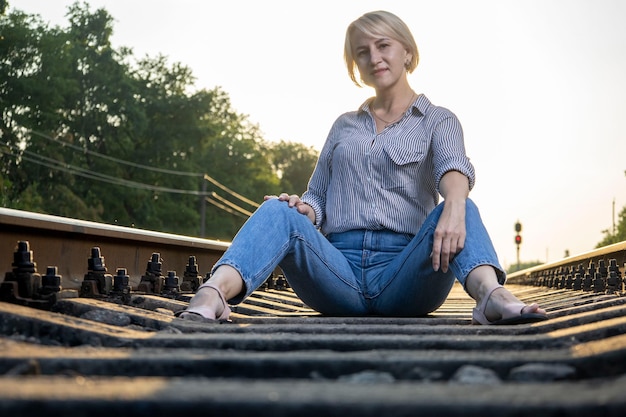 Photo a woman in jeans is sitting on a railway track