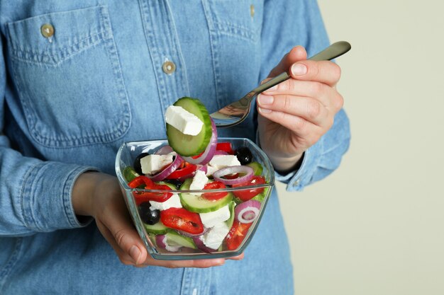 Woman in jeans shirt eats greek salad