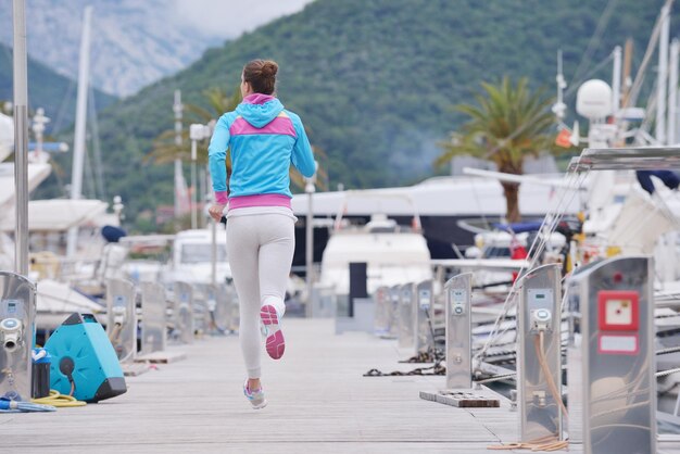 woman jogging at early morning with yacht boats in marina