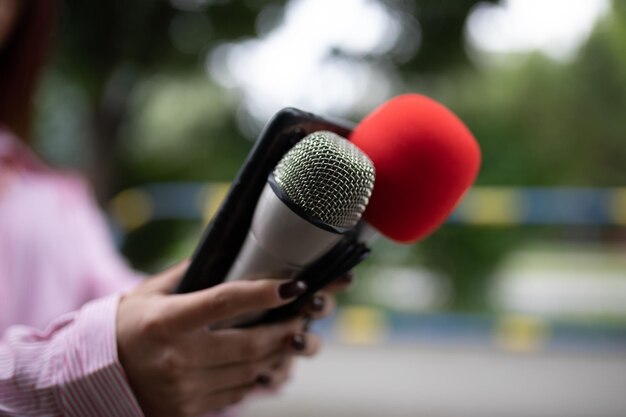 Женщина-журналист на мероприятии с микрофонами и записью записей на смартфон-диктофон