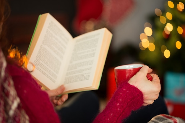 Photo woman in jumper reading and drinking coffee