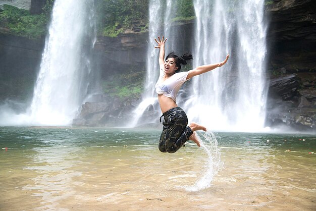 Foto donna che salta contro la cascata