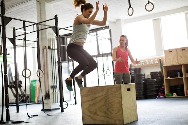 Photo woman jumping on box with fitness trainer