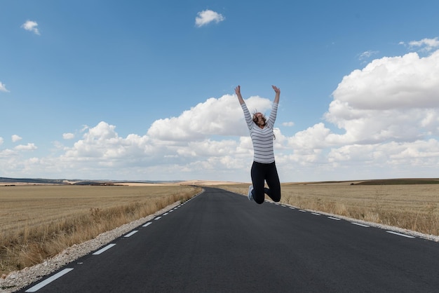 写真 空に向かって道路にジャンプする女性