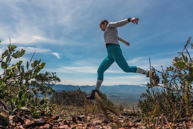 Woman jumping over rocks in mountain