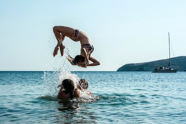 woman jumping in sea against clear sky