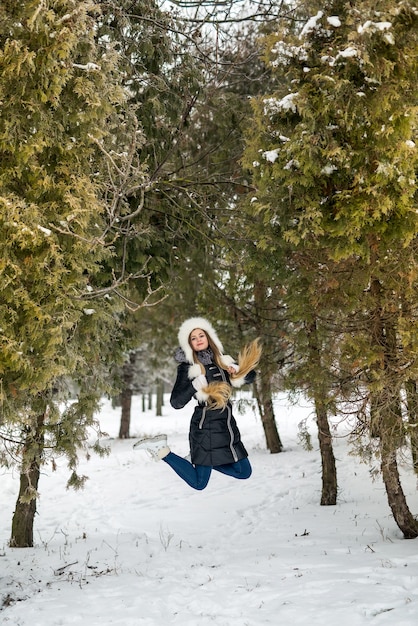 Woman jumping between trees in winter park