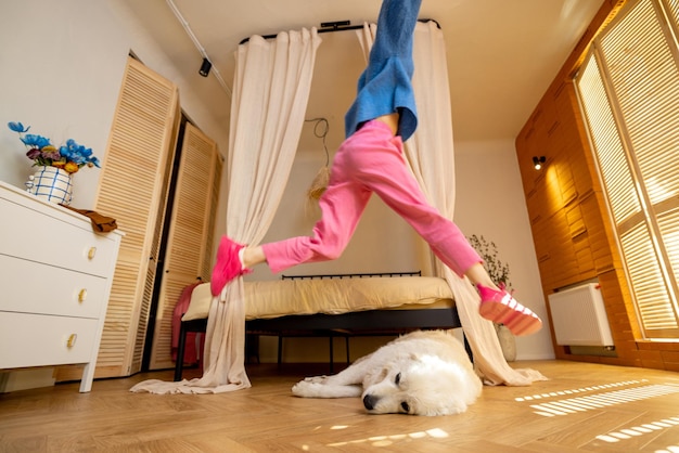 Woman jumps over a sleeping dog at home