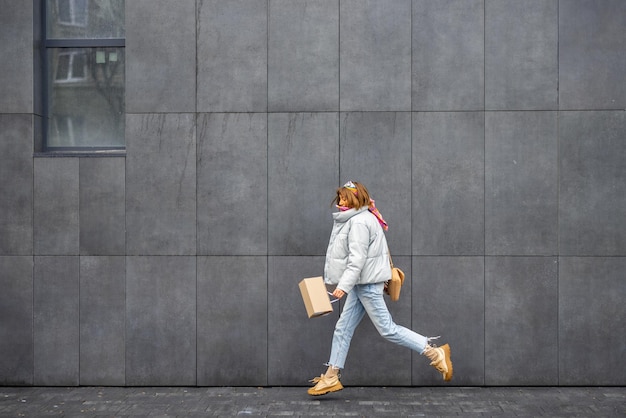 Woman jumps while walking near the wall outdoors