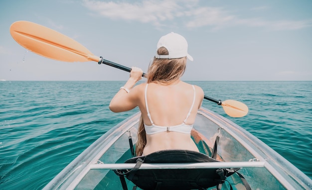 Woman in kayak back view happy young woman with long hair floating in transparent kayak on the