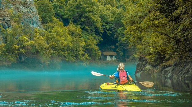 The woman in  kayak in fog on mountain lake