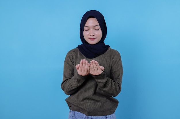 Woman keeps hands in praying gesture, asks allah for good health, believes in wellness has veiled head